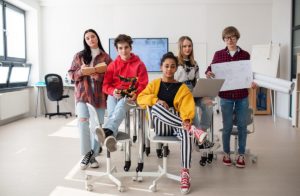 Group of students sitting and posing together in robotics classroom