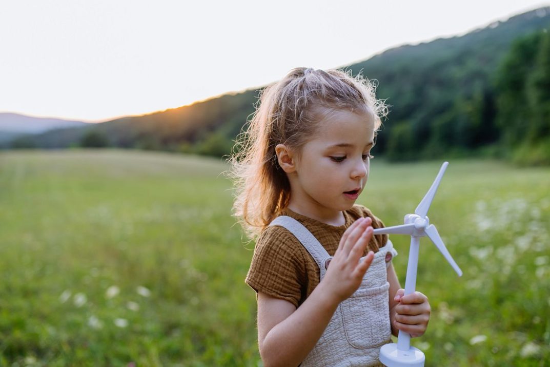 Child playing with toy wind turbine; renewable energy lesson plans concept