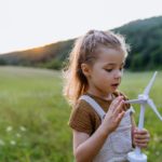 Child playing with toy wind turbine; renewable energy lesson plans concept