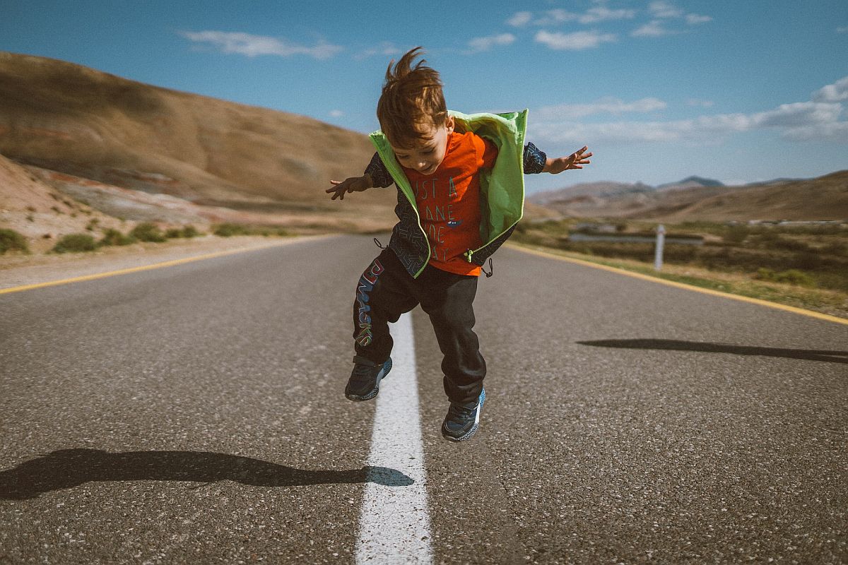 Little boy jumping in an empty street; add physical activity concept.