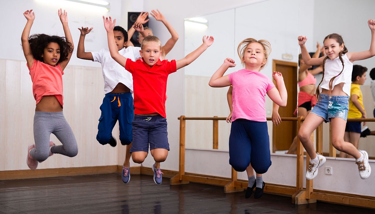 Young children jumping in a dance classroom; add physical activity concept.