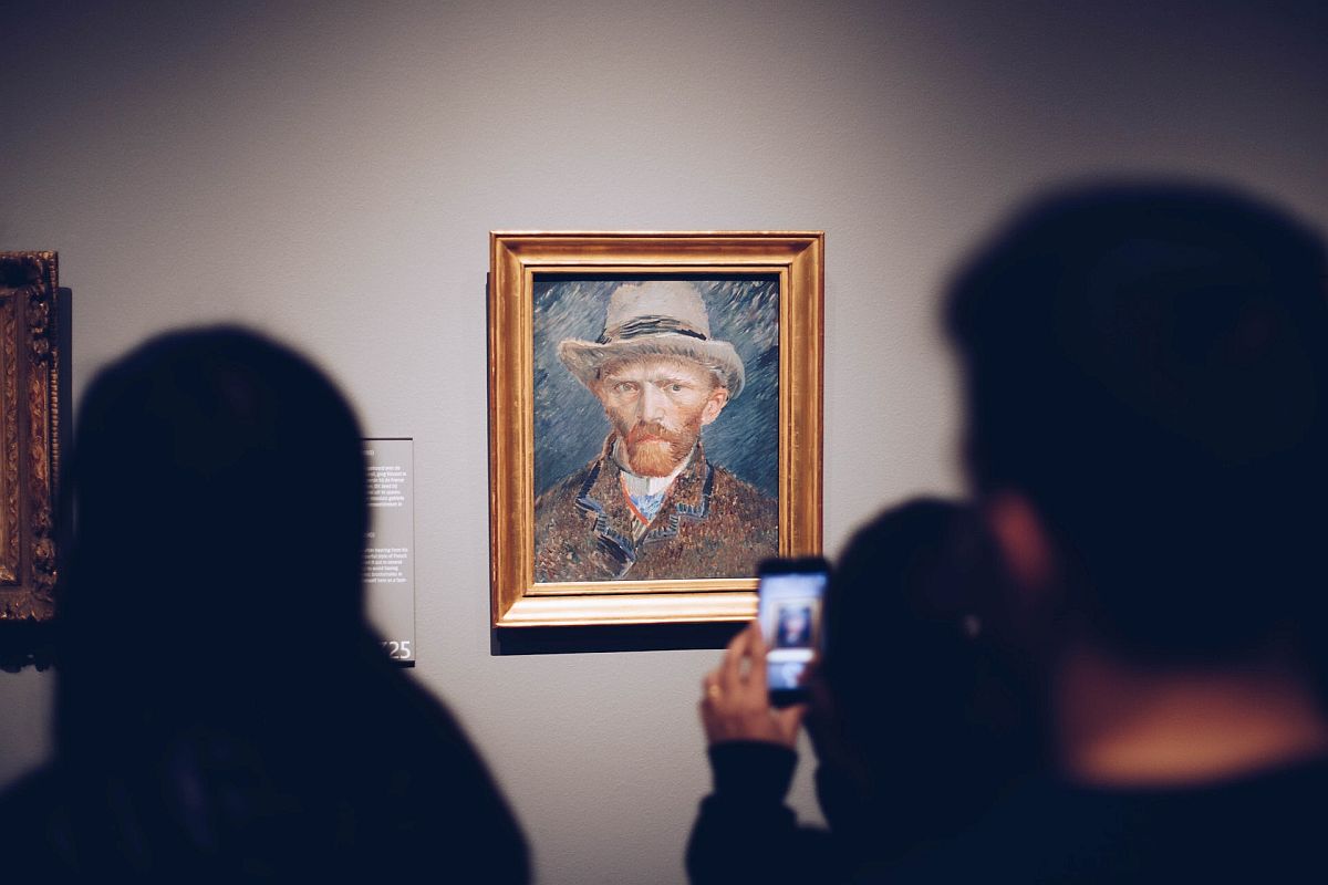 Visitors looking at Van Gogh self-portrait in museum; community destinations concept
