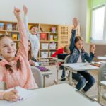 Children in classroom, raising their hands; nano-learning concept.