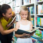 Young girl in library, choosing a book; fun literature lesson plans concept