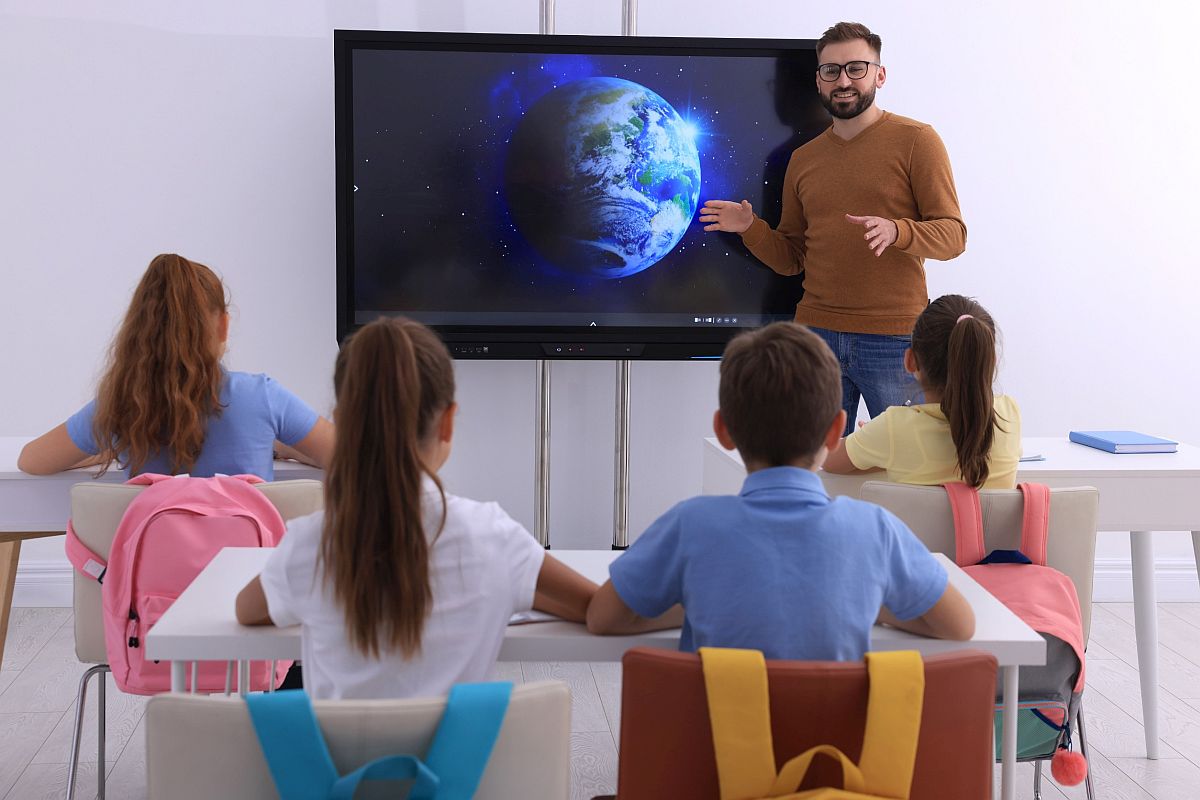 teacher using a digital screen with young students; technology grants concept