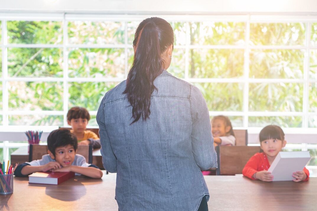 Teacher in front of small classroom; extra resources concept