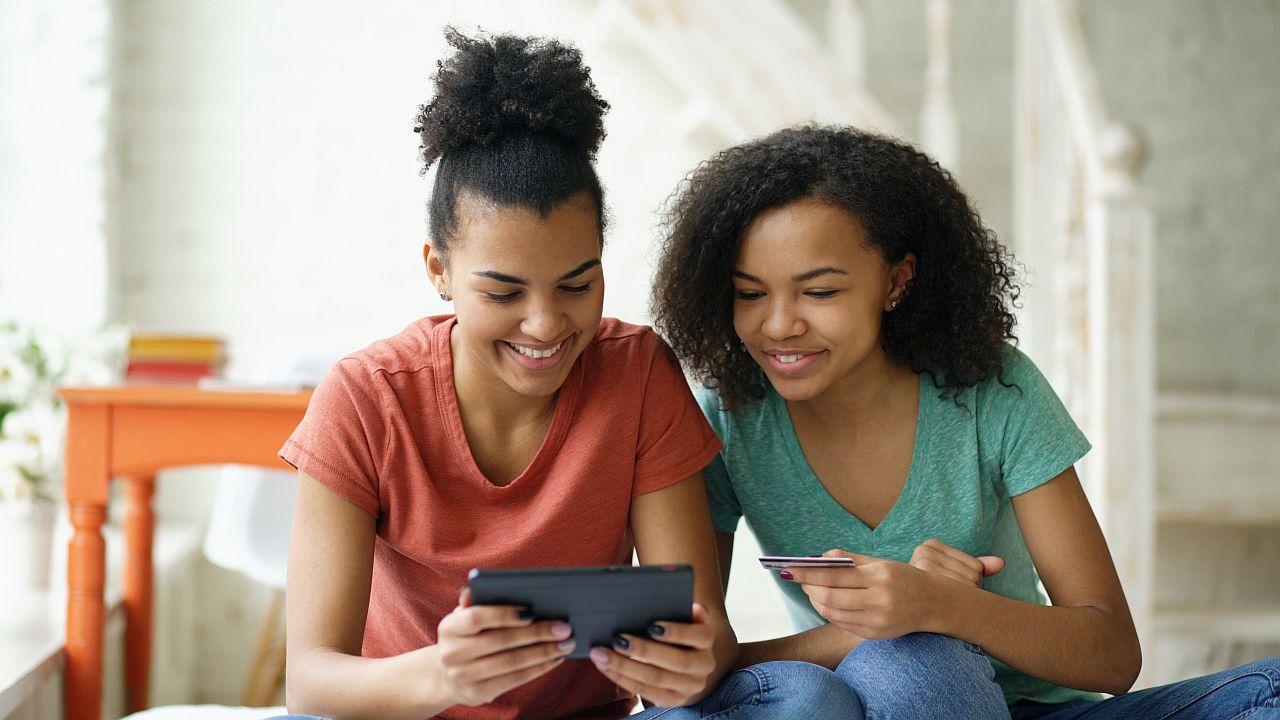 Girls using credit card to shop online; financial literacy concept