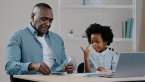 Man counting money with child; financial literacy concept