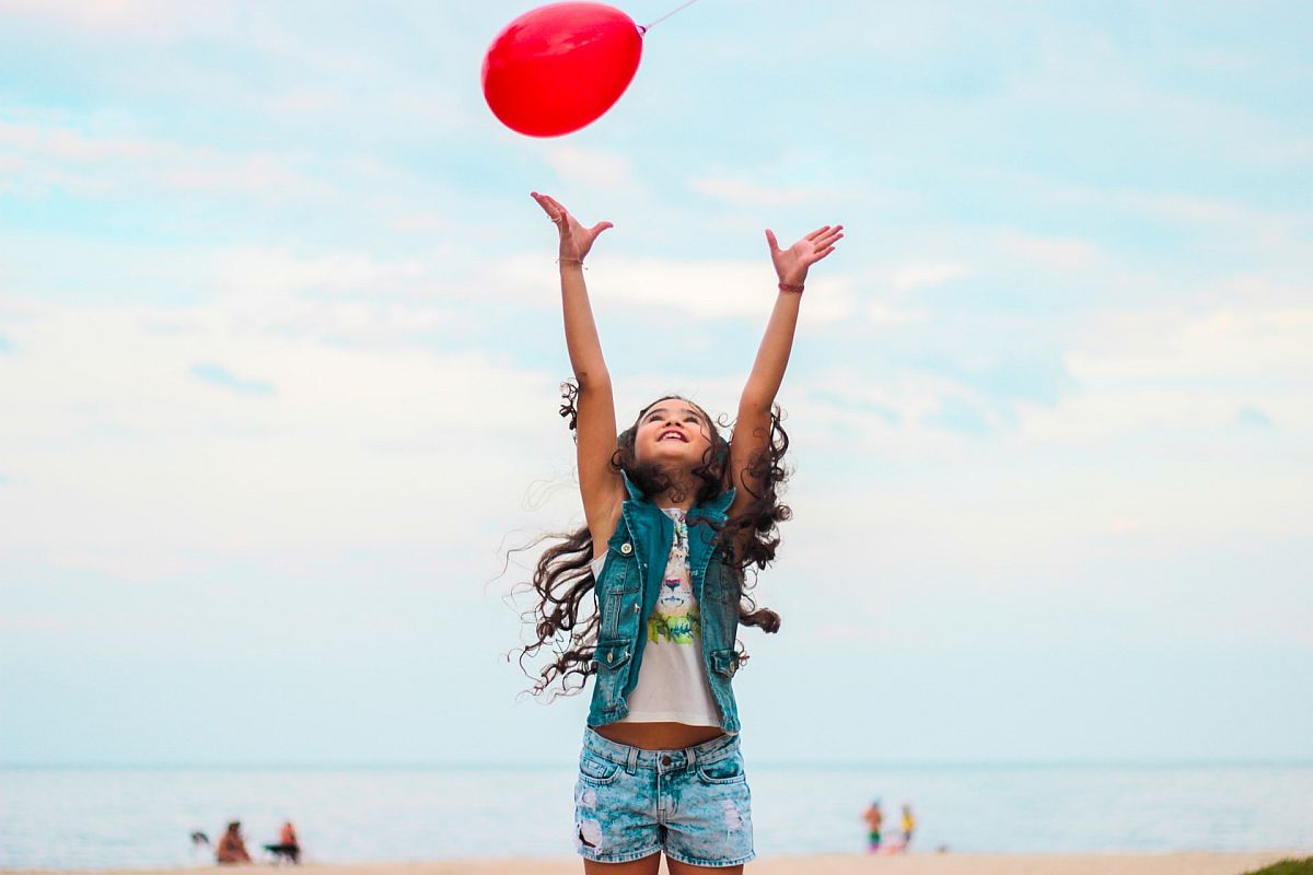Young girl playing with balloon on beach; make math fun concept