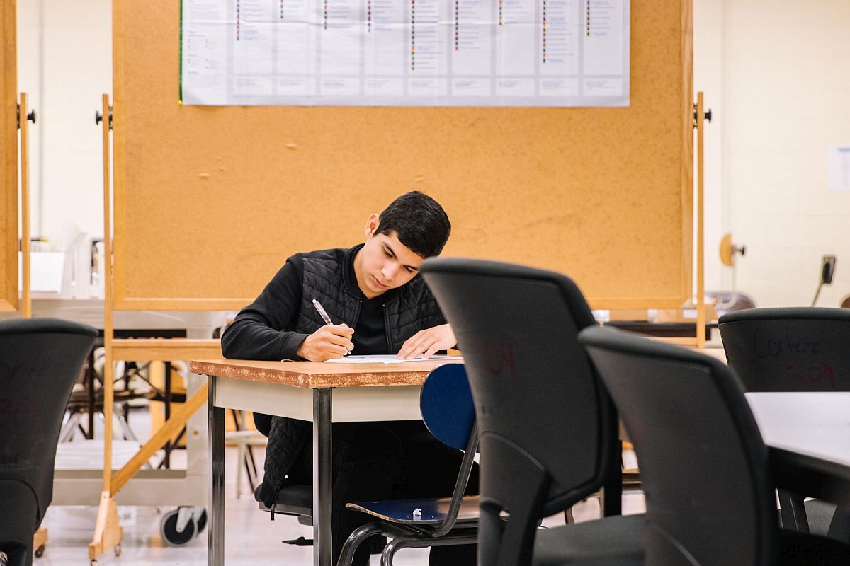 student alone in classroom writing at a desk; math specialists concept