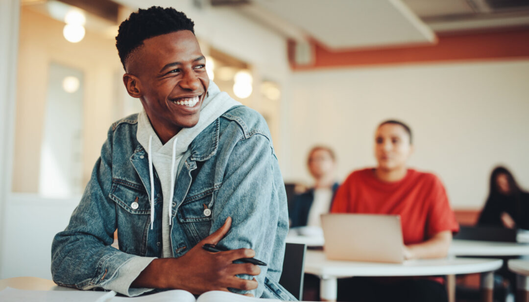 Smiling student sitting at a desk in the classroom; independent study projects concept