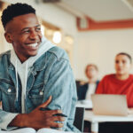 Smiling student sitting at a desk in the classroom; independent study projects concept