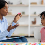 Speech therapist working with young girl on sounds; speech therapists concept