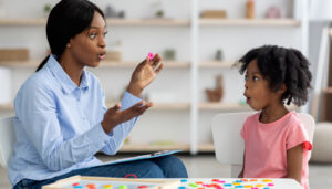 Speech therapist working with young girl on sounds; speech therapists concept