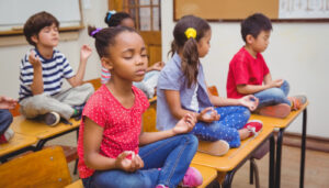 Children meditating at school; reflection in the classroom concept