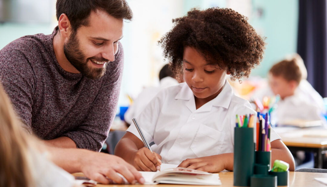 Smiling teacher working one-on-one with student; Four-Day School Week concept