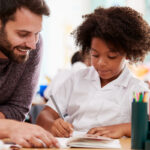 Smiling teacher working one-on-one with student; Four-Day School Week concept