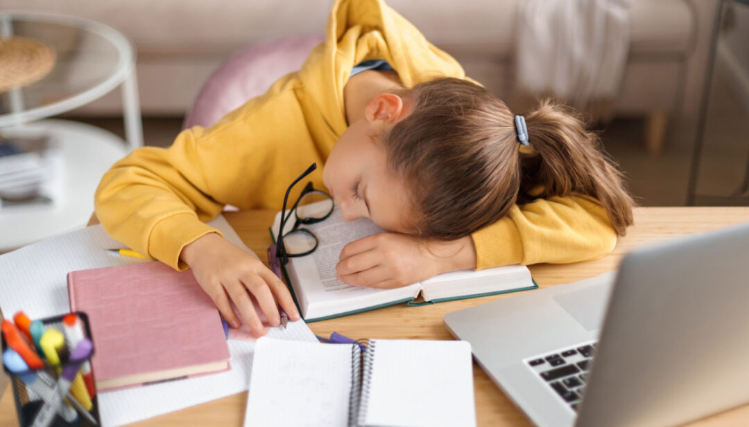 Student sleeping at her desk; later school start times concept