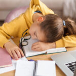 Student sleeping at her desk; later school start times concept