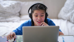 Girl at home using laptop and headphones; internet privacy lessons concept