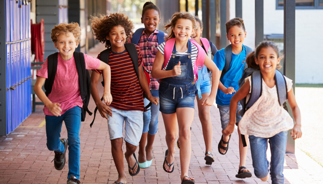 School kids running in elementary school outdoor corridor; year-round school concept
