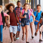 School kids running in elementary school outdoor corridor; year-round school concept